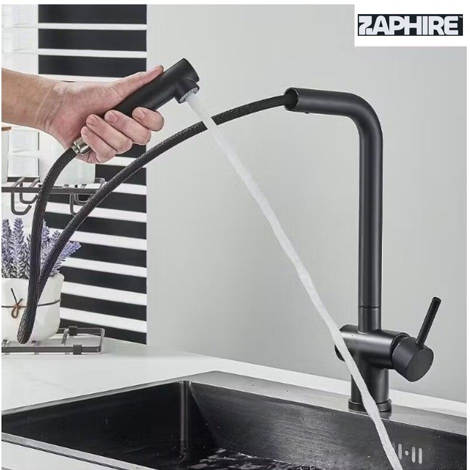 Grifo de cocina negro que vierte agua en un fregadero negro, situado frente a una pared de rayas blancas y negras.