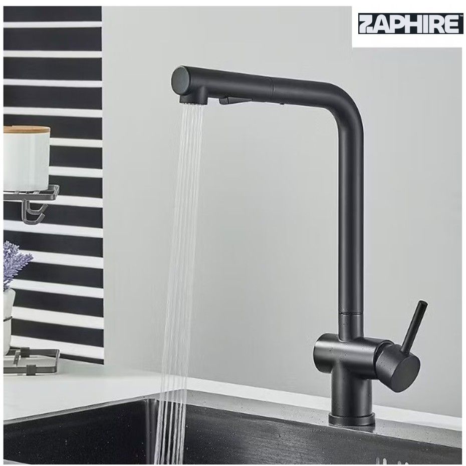 Grifo de cocina negro que vierte agua en un fregadero negro, situado frente a una pared de rayas blancas y negras.