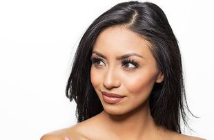 Woman with dark hair looking off to the side, with a light complexion and makeup.