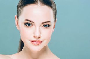 Woman with fair skin and blue eyes, looking towards the viewer, with a neutral expression. Light teal background.