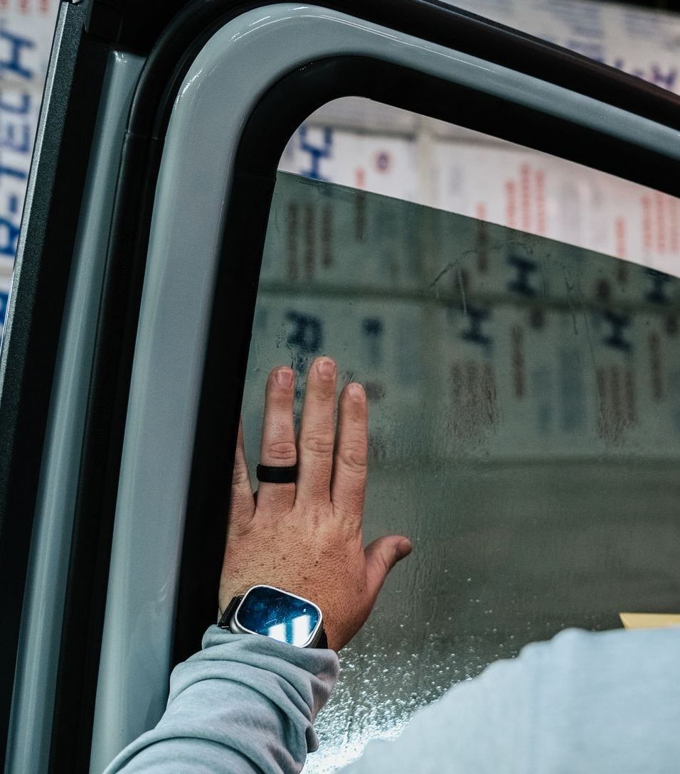 A person wearing a watch and a ring is reaching out of a car window.