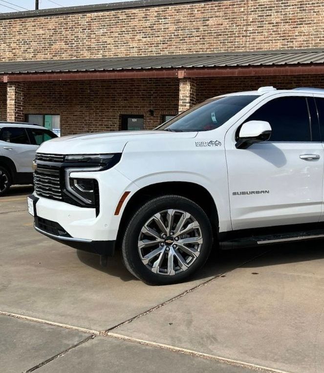 A white suv is parked in front of a brick building.