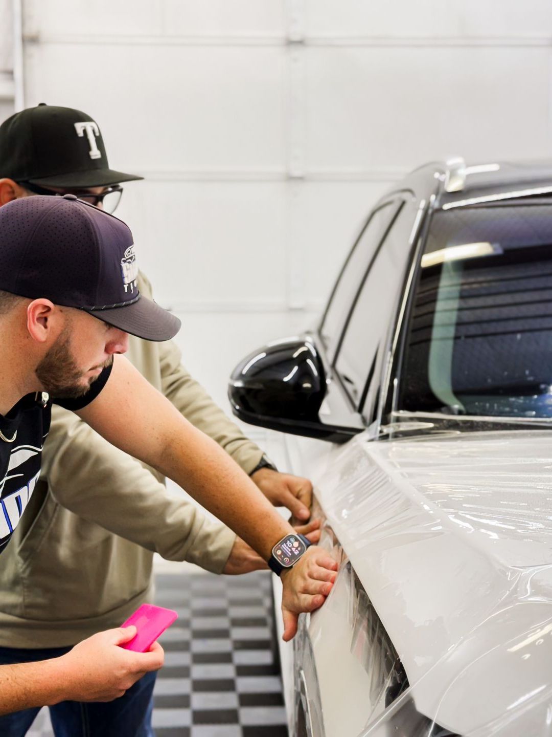 Two men are working on a car in a garage.