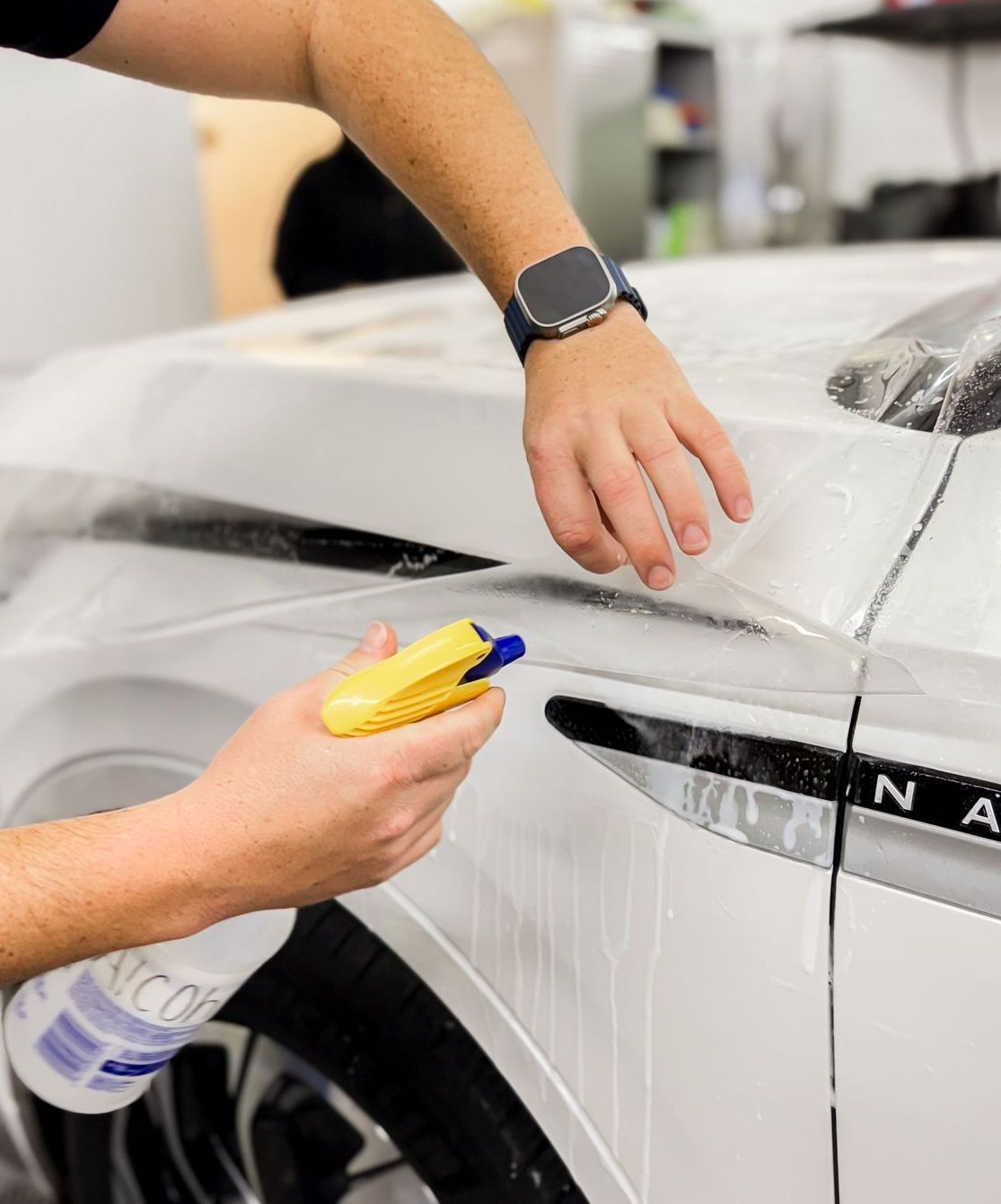 A person is spraying a car with a spray bottle.