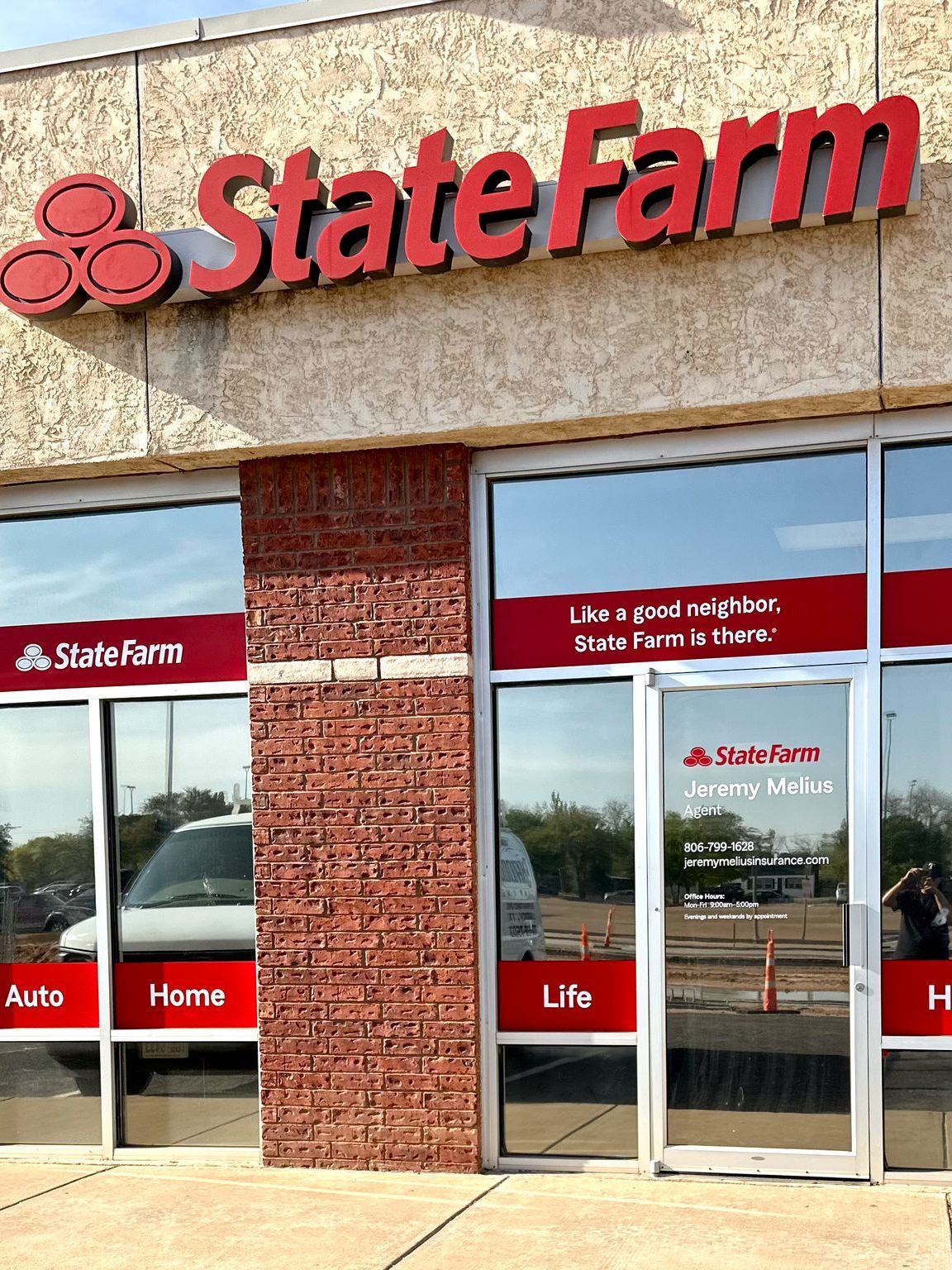 The front of a state farm store with a white van parked in front of it.
