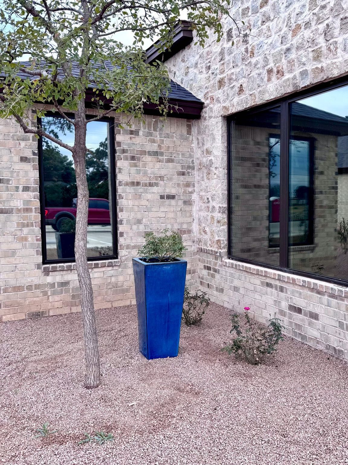 A blue planter is sitting in front of a brick building.