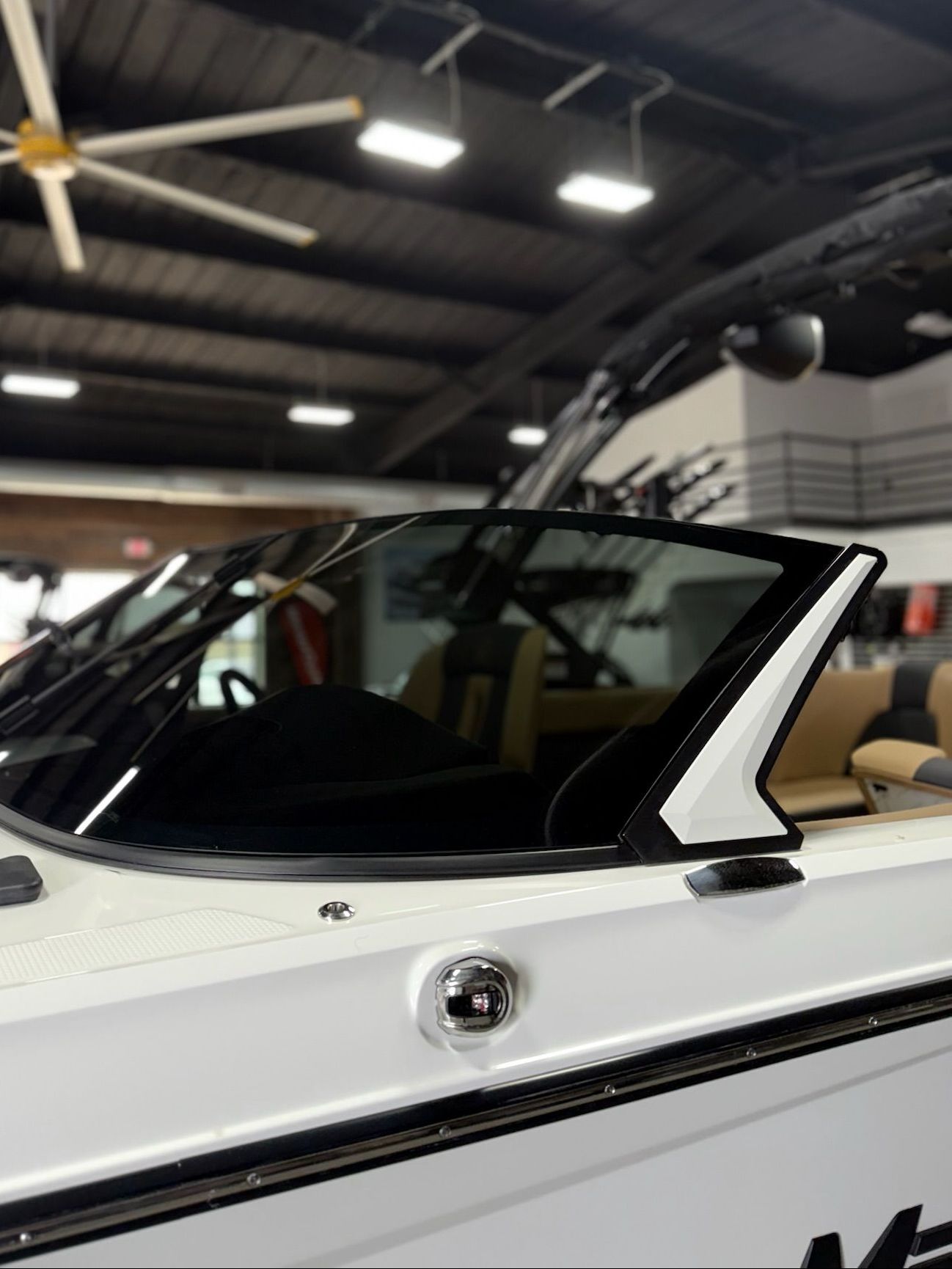A white boat in a showroom with a ceiling fan