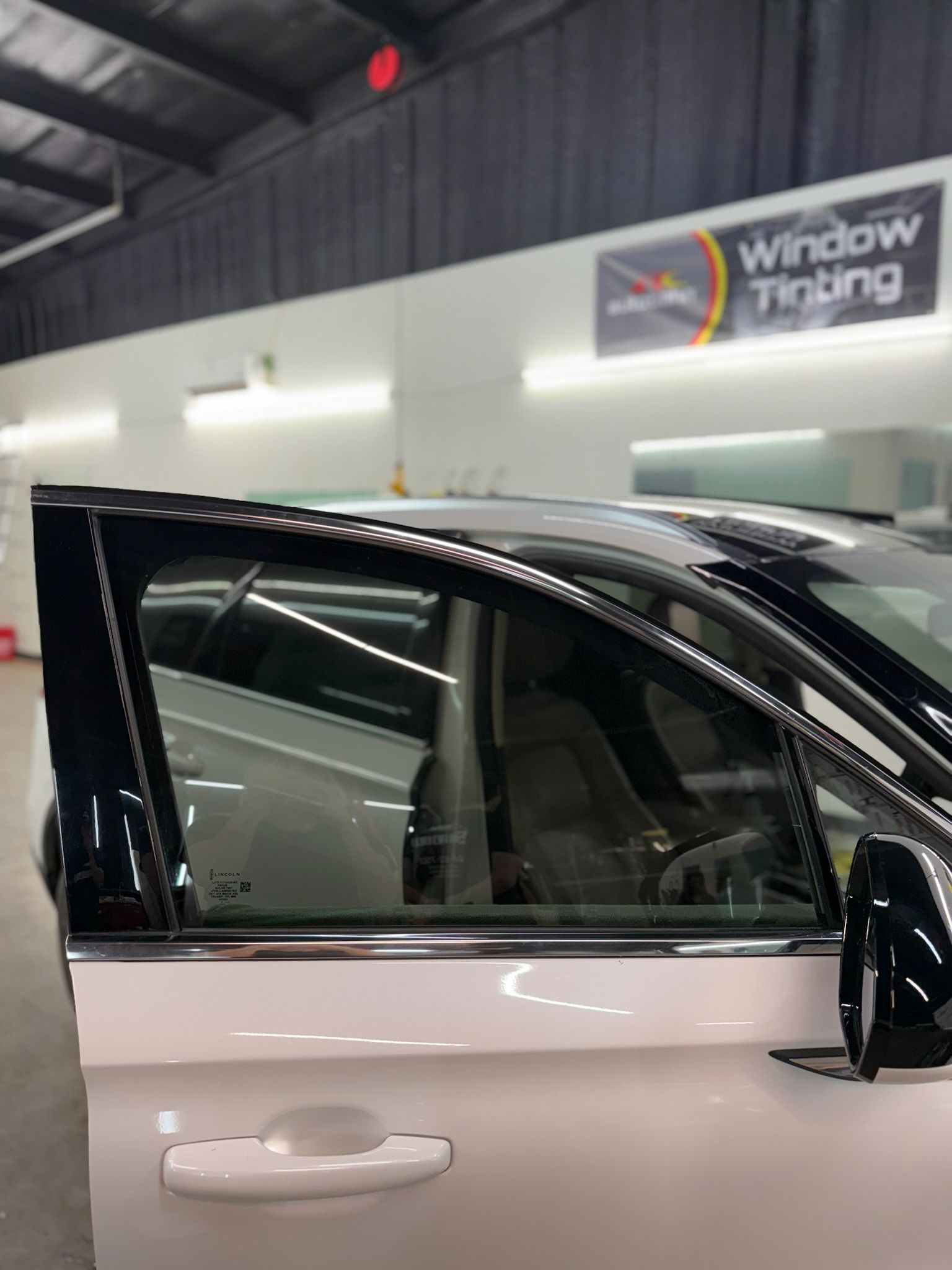 A white car is parked in a garage with its door open.