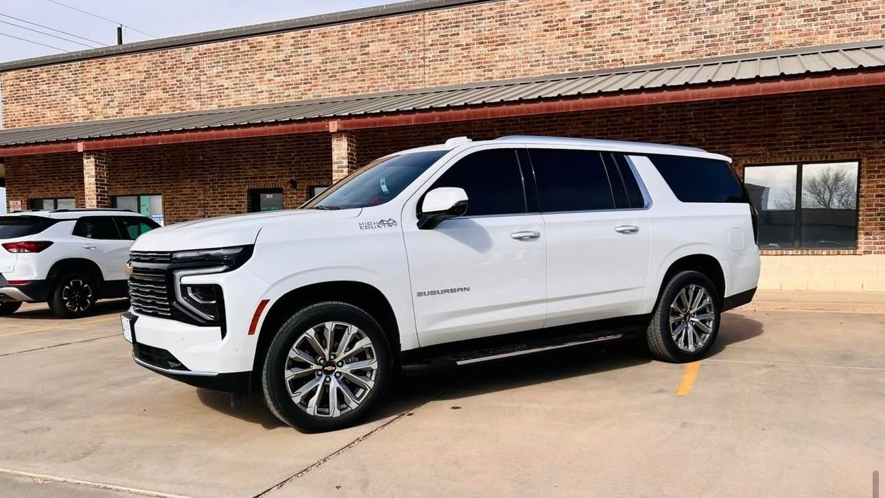 A white suv is parked in front of a brick building.