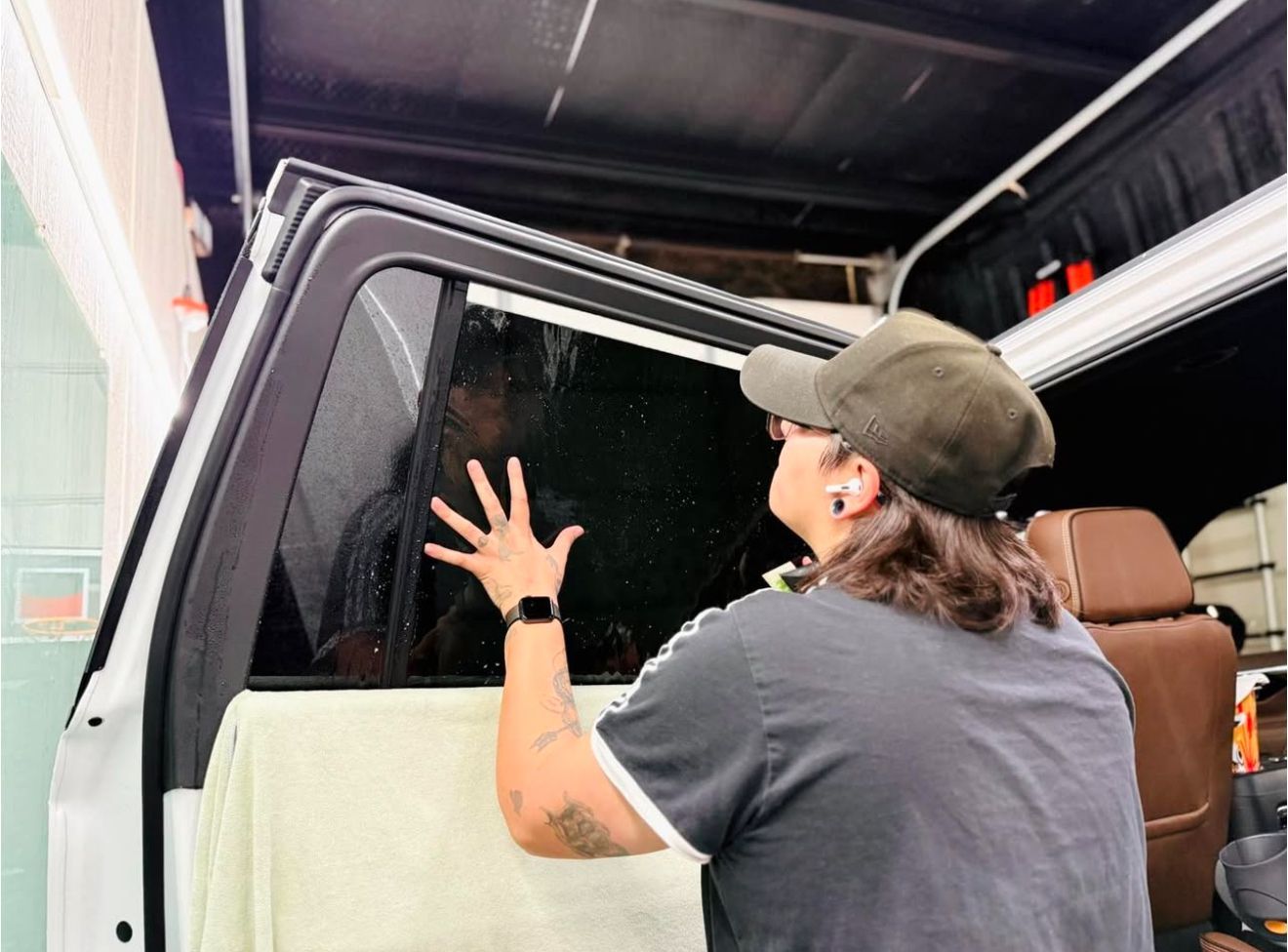 A woman is applying window tinting to a car window.