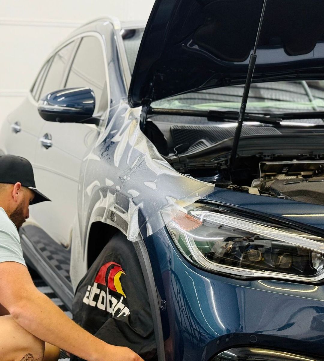 A man is working on a car with the hood open.