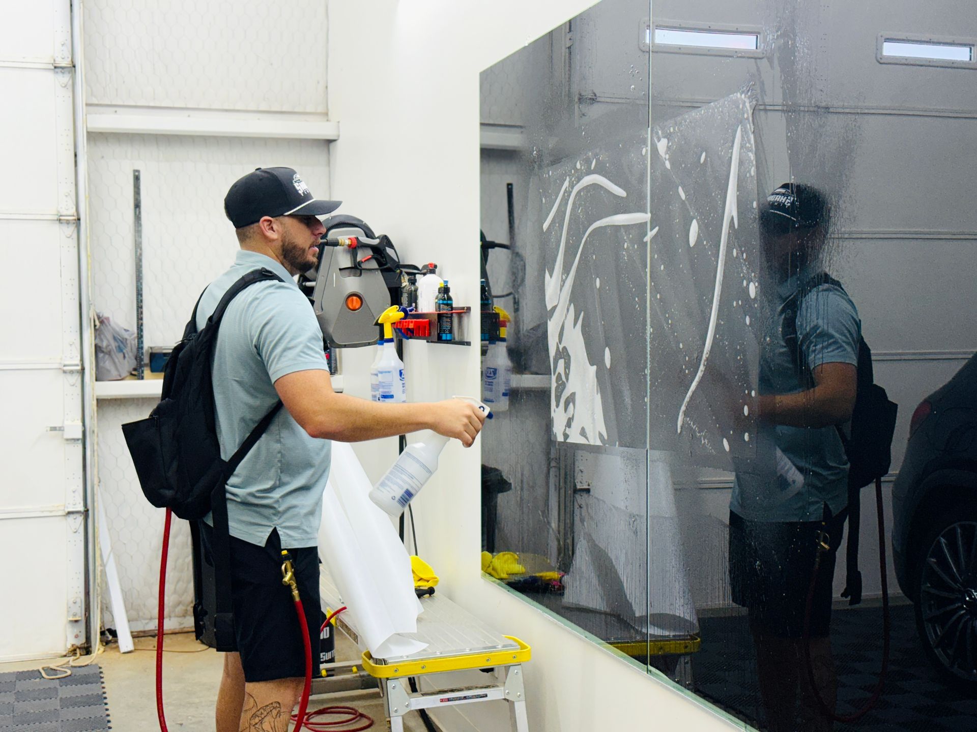 A man is standing in front of a mirror in a garage.