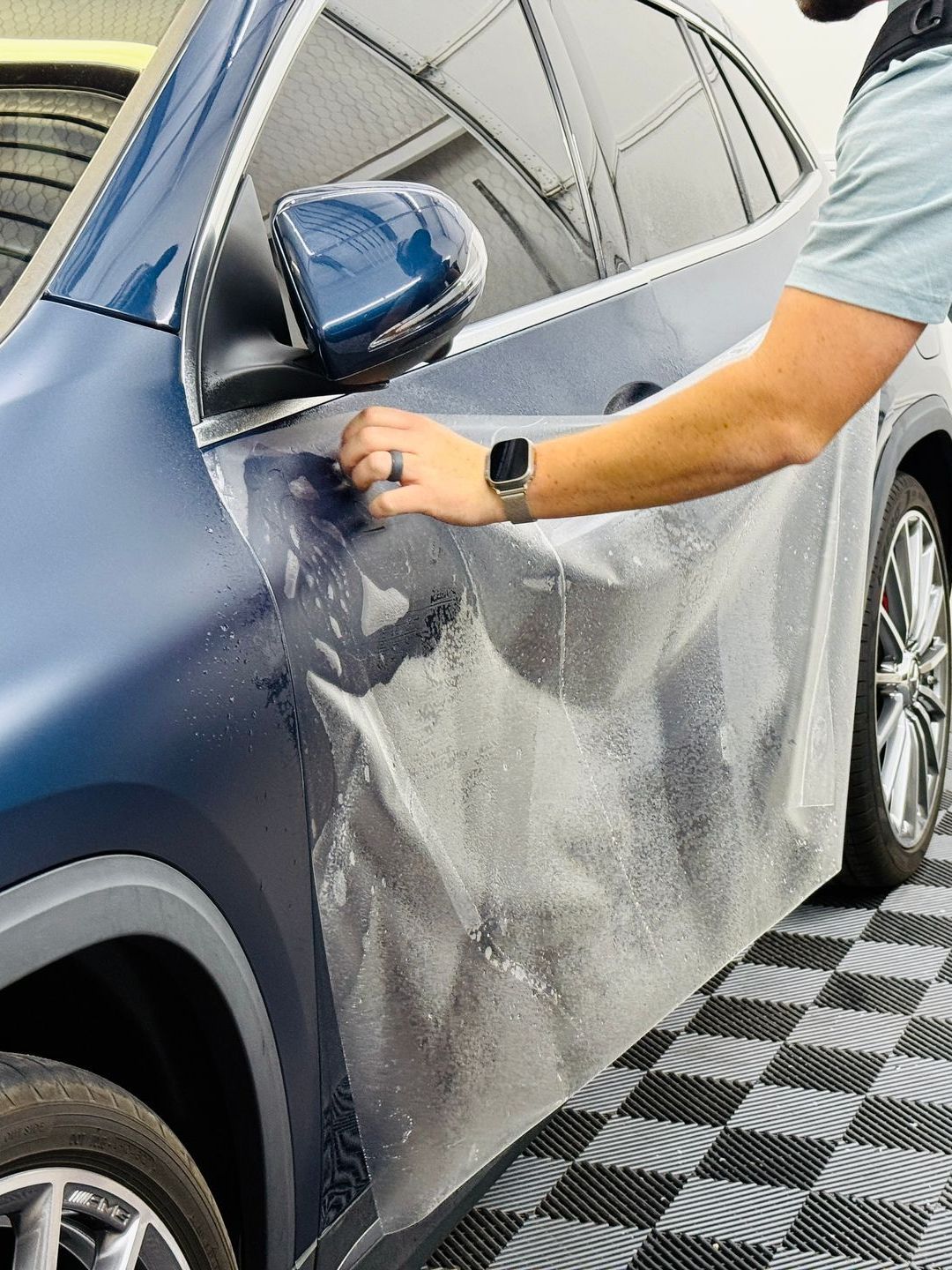 A man is wrapping a car with plastic wrap.