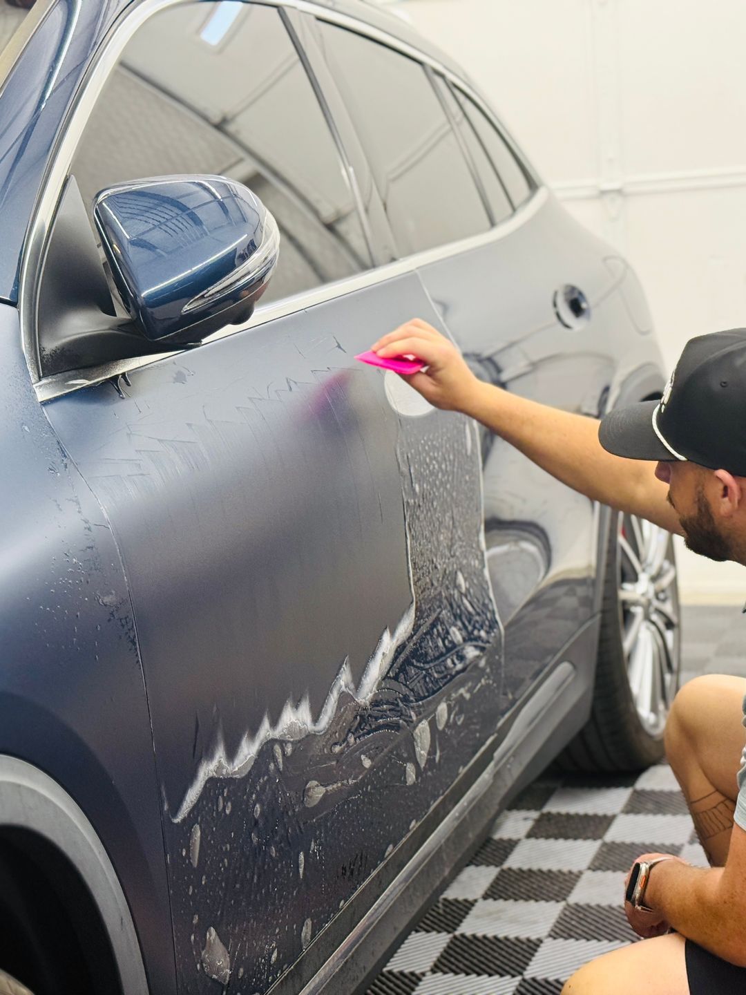 A man is wrapping a car with a pink sponge