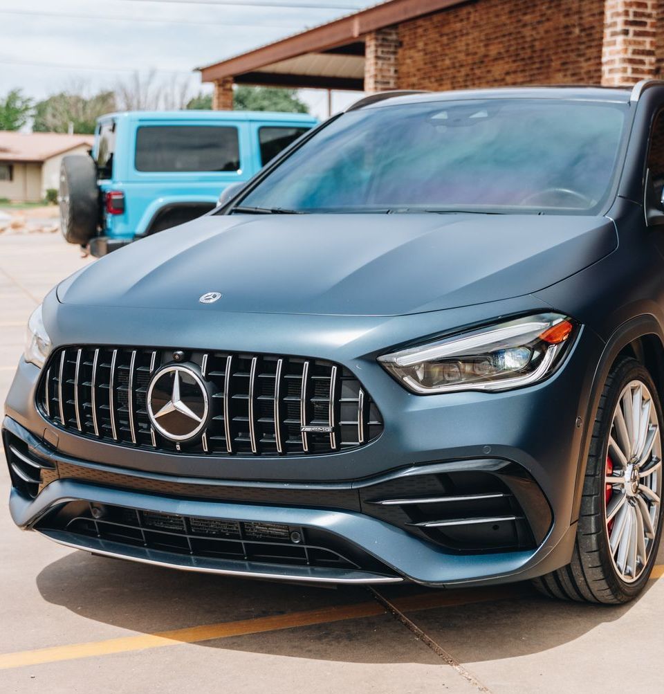 A blue mercedes is parked in a parking lot