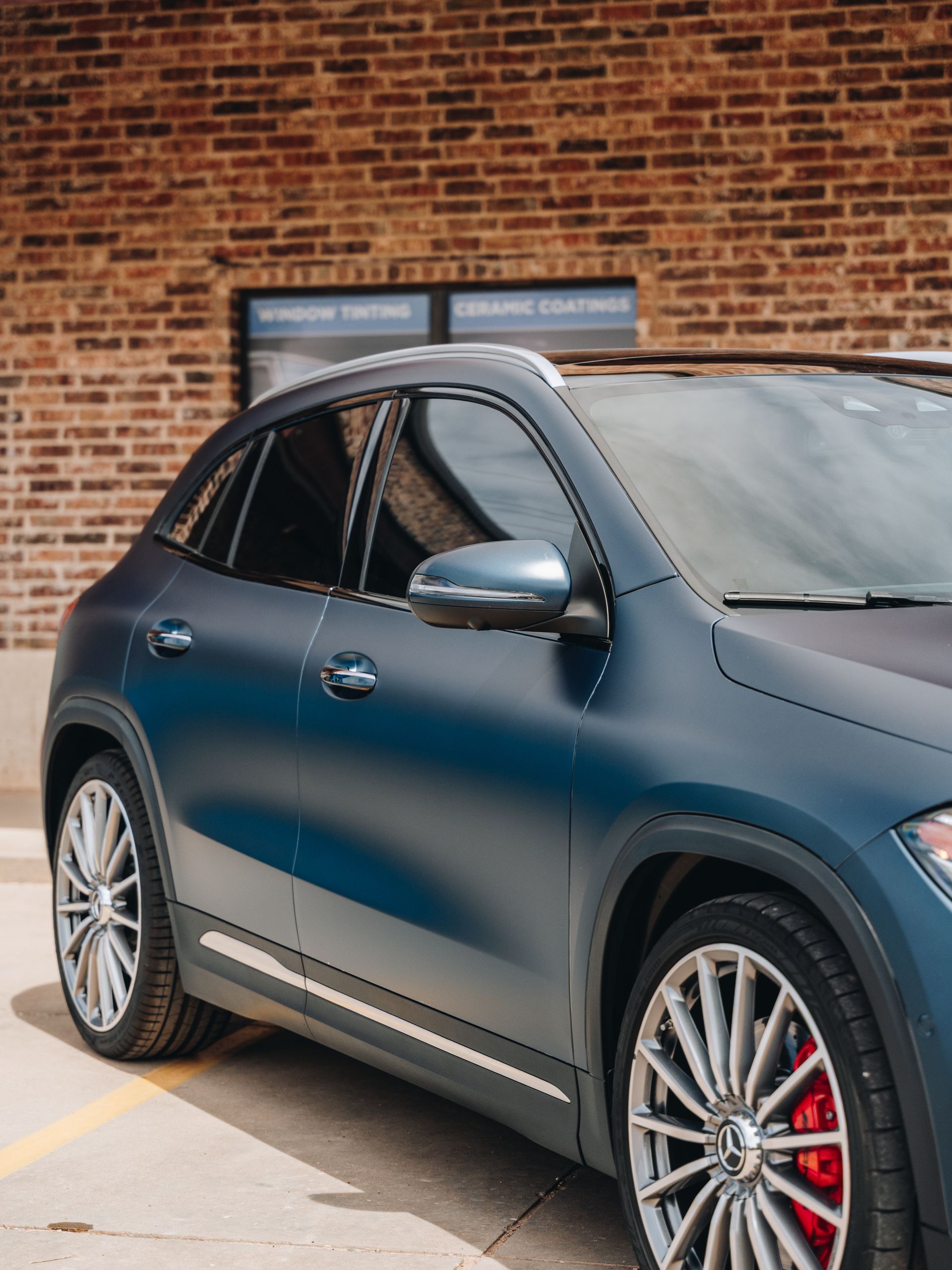 A blue car is parked in front of a brick building.