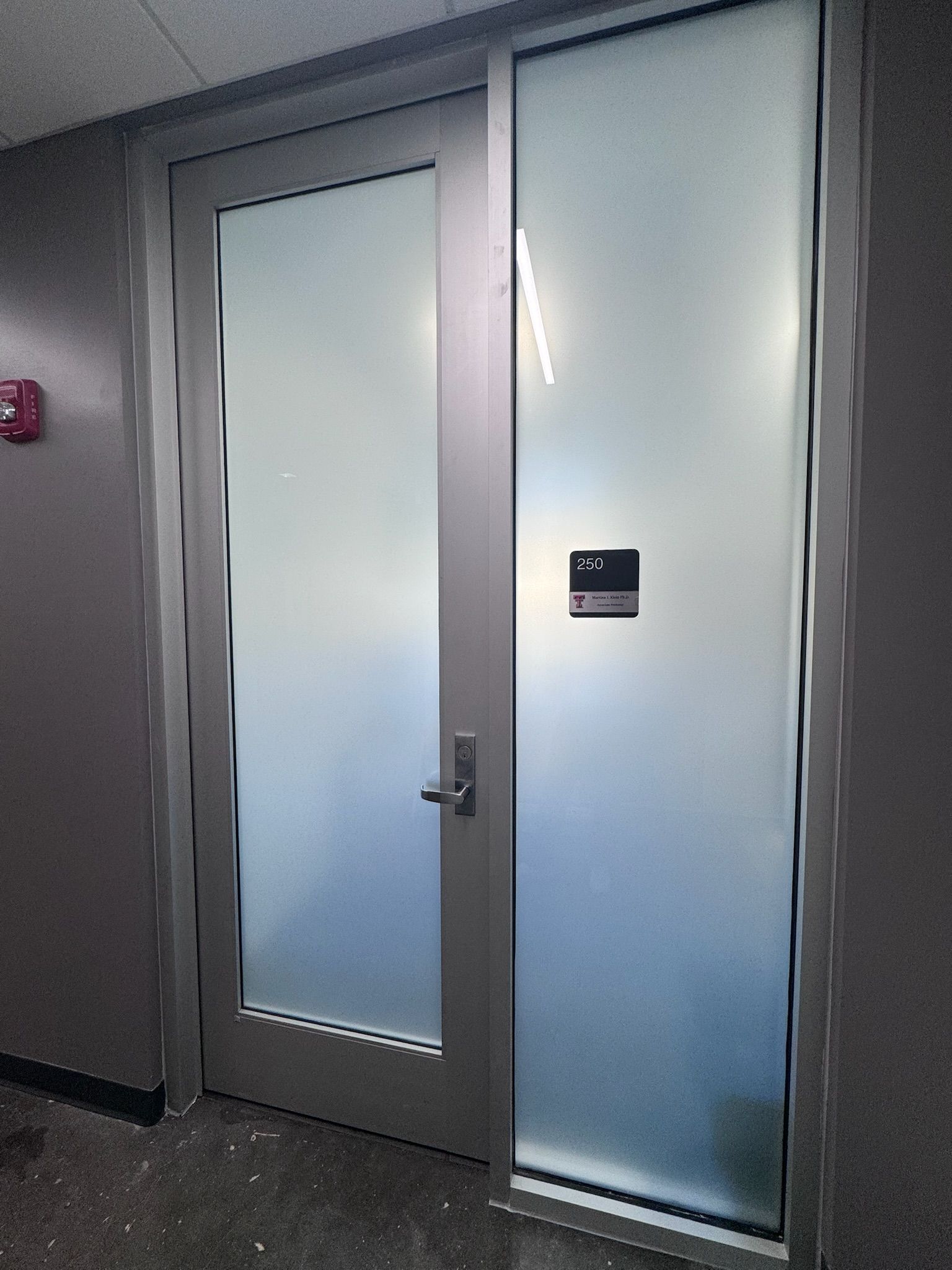 A door in a hallway with a fire extinguisher on the wall