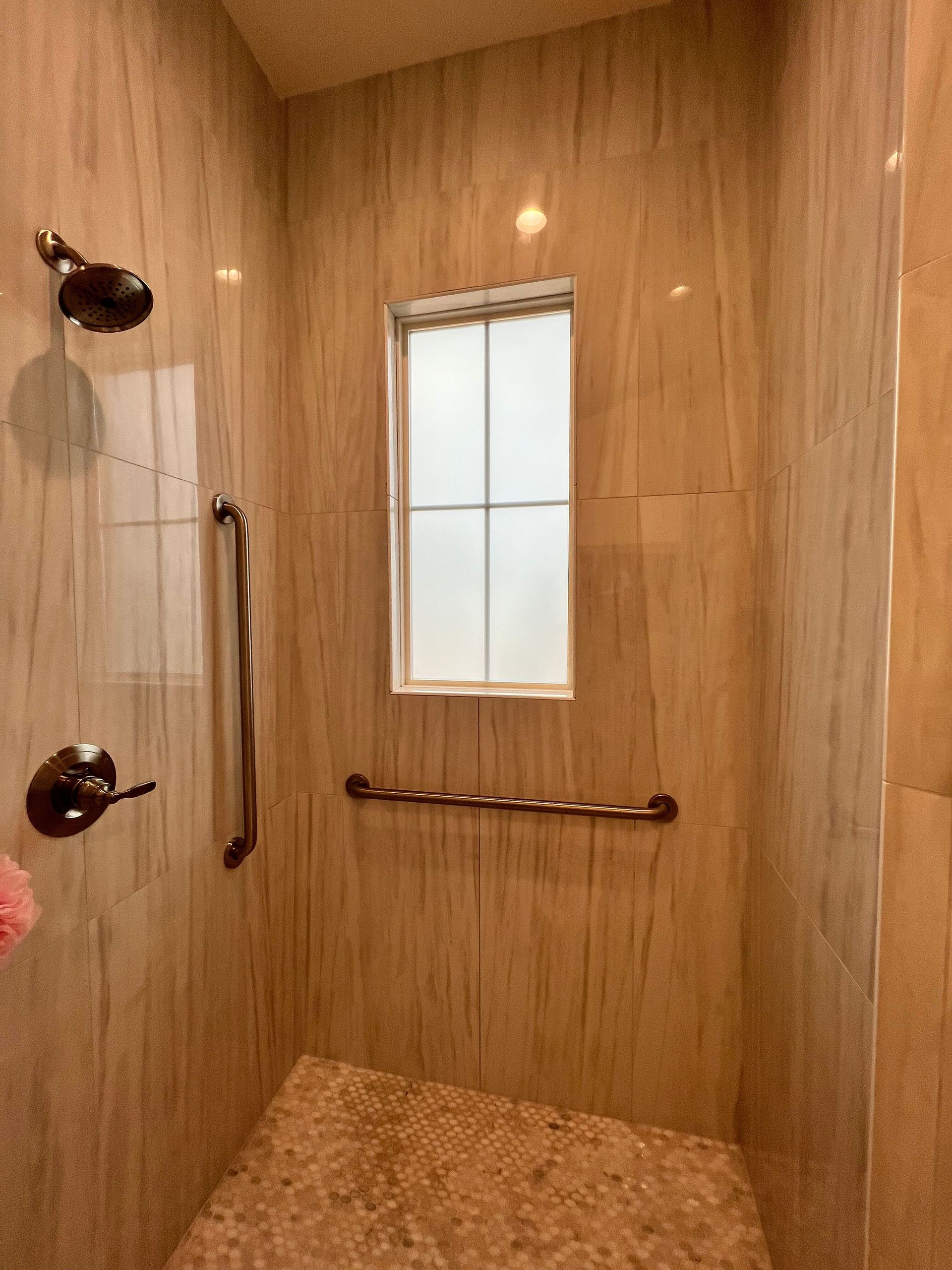 A bathroom with a walk in shower and a window.