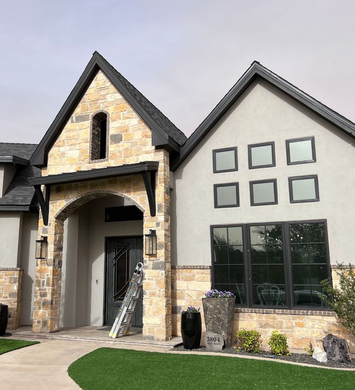 A house with a lot of windows and a ladder in front of it