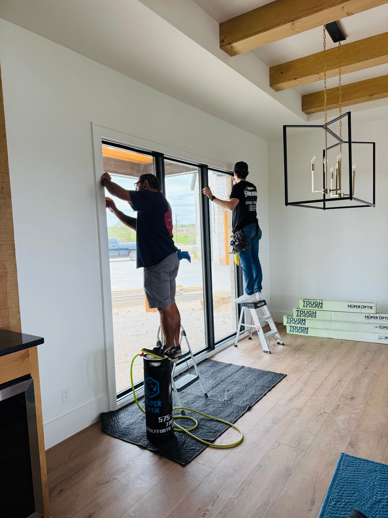Two men are working on a sliding glass door in a living room.