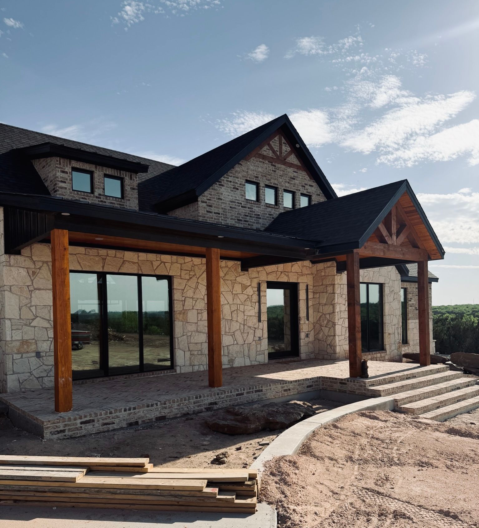 A large stone house with a black roof is being built.