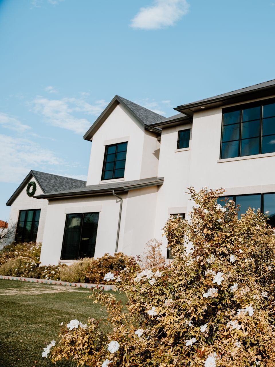 A large white house with a lot of windows and flowers in front of it.