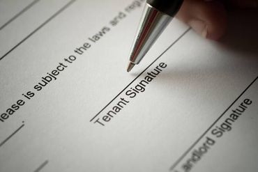 Pen signing a tenant signature line on a lease form