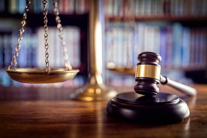 Law book and judge’s gavel on a desk with blurred bookshelves in the background