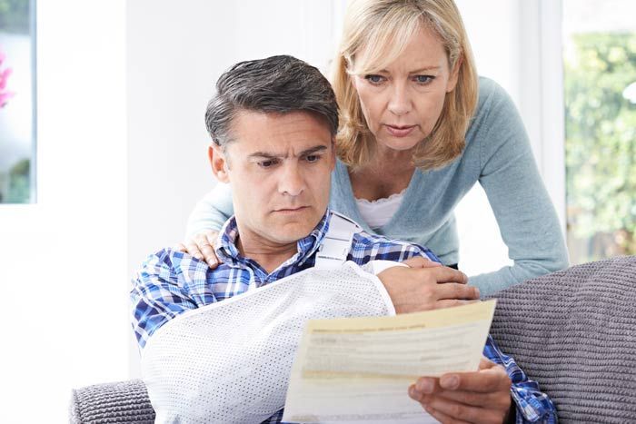 Two people looking worried at a bill on a couch in a bright living room