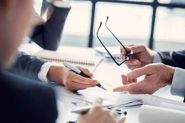 Hands pointing at documents during a business meeting at a bright table