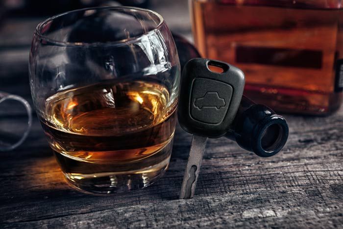 Whiskey glass on rustic table beside car key fob