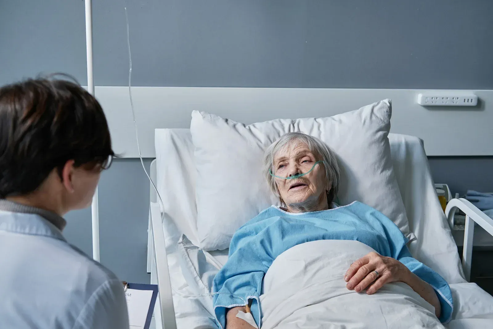 Doctor talking to a patient in a hospital bed with oxygen tubes.
