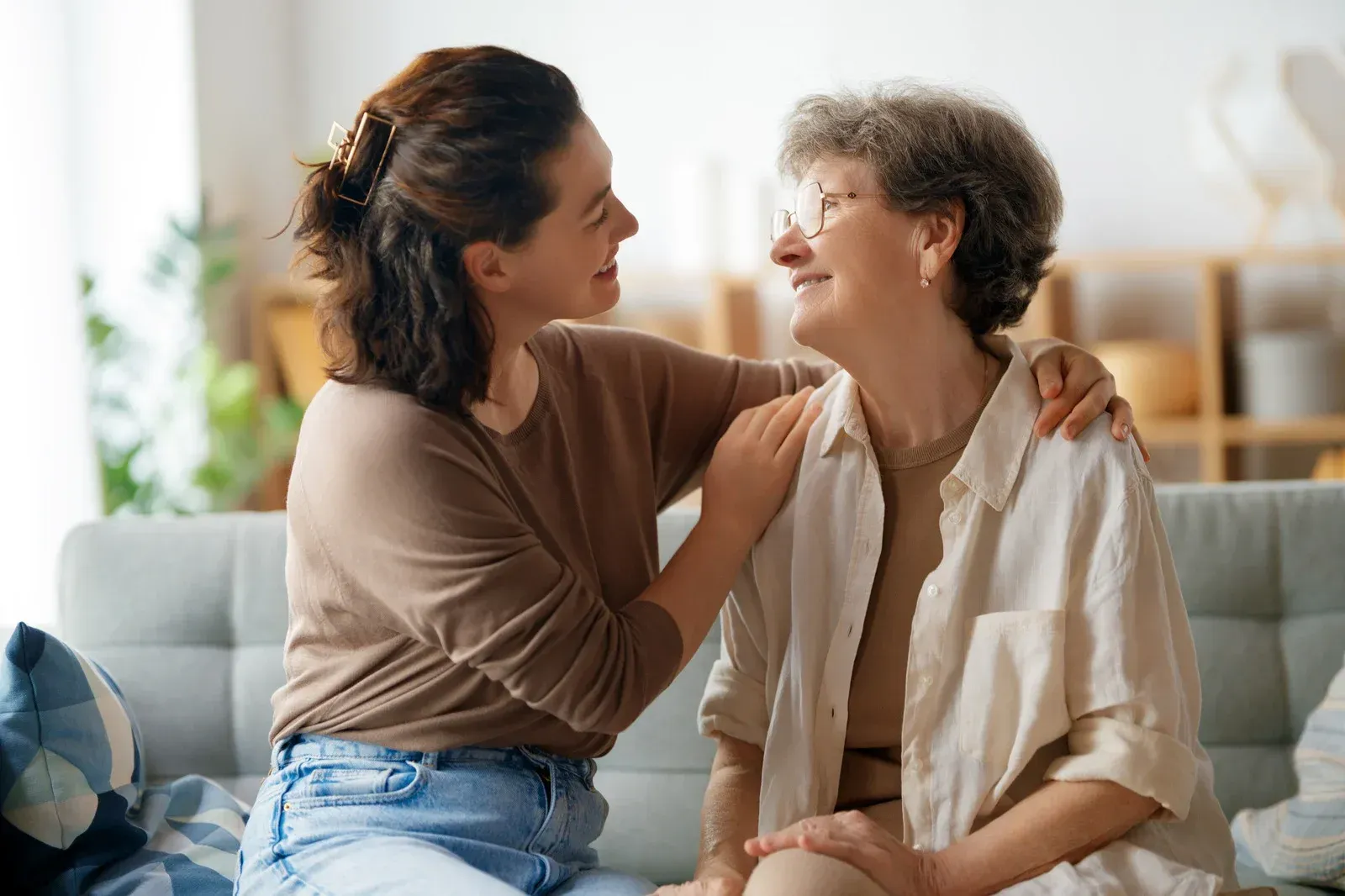Caregiver assists a person with a walker towards a brick home.