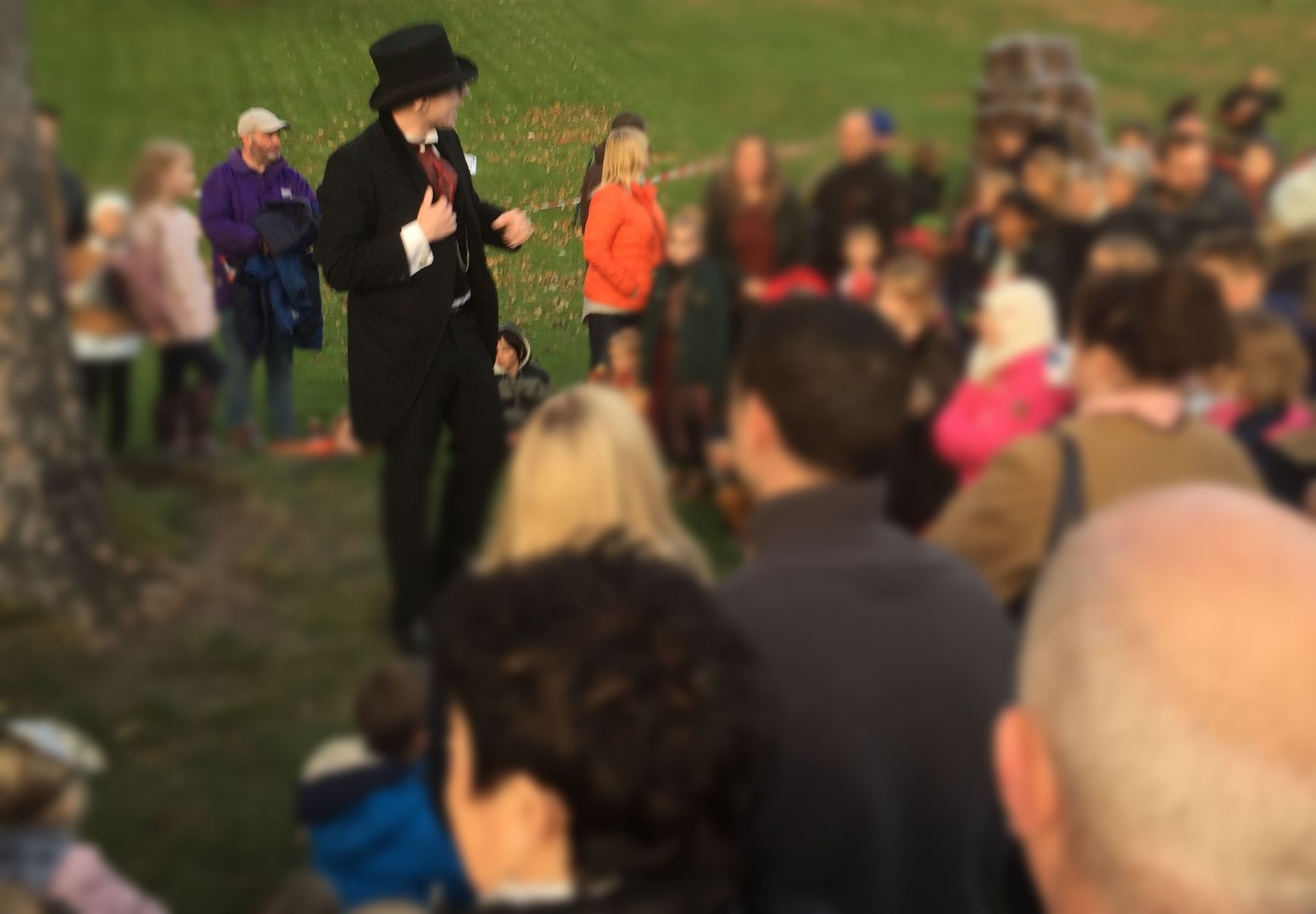 Storyteller Ben Glover telling a spooky story to a crowd of people at a halloween event.