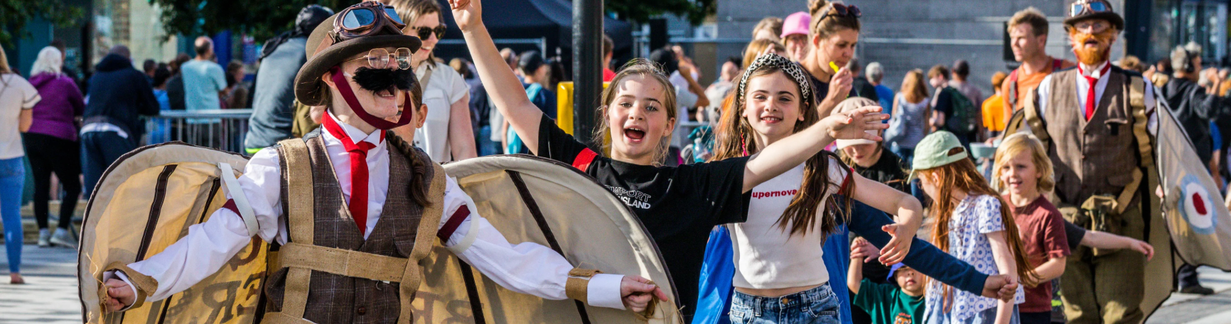 Feasible Ferret Theatre’s walkabout act The Wrong Brothers interacting with a laughing audience members at a street event.
