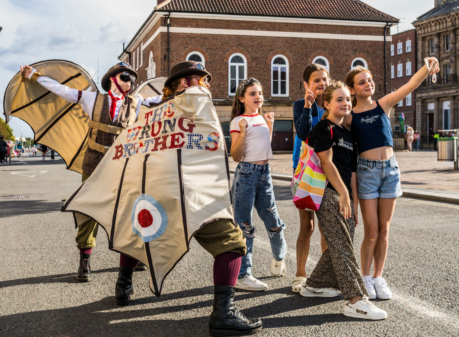 Feasible Ferret Theatre’s walkabout act The Wrong Brothers posing with young people for a photo during a street performance.
