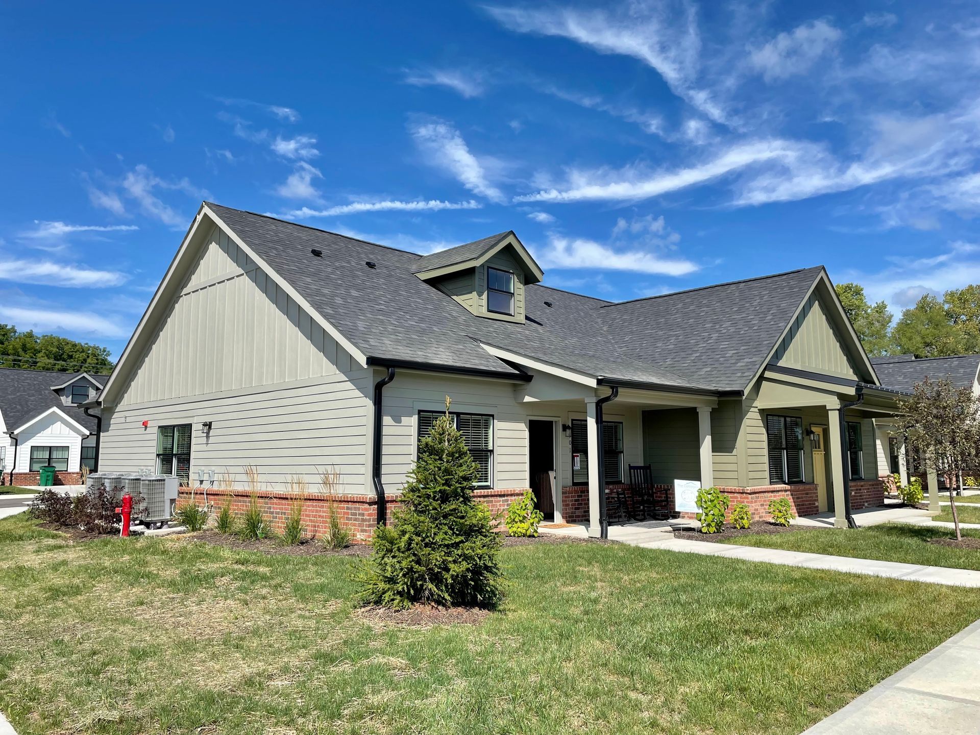 A large house with a gray roof is sitting on top of a lush green lawn.