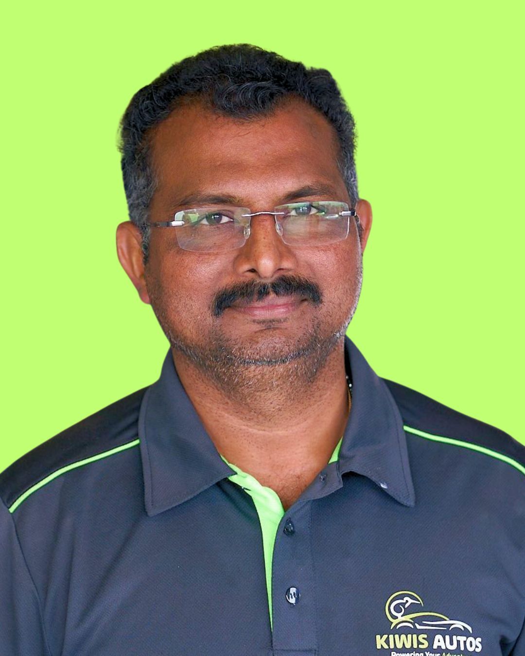 A man with glasses and a mustache is wearing a black and green shirt.