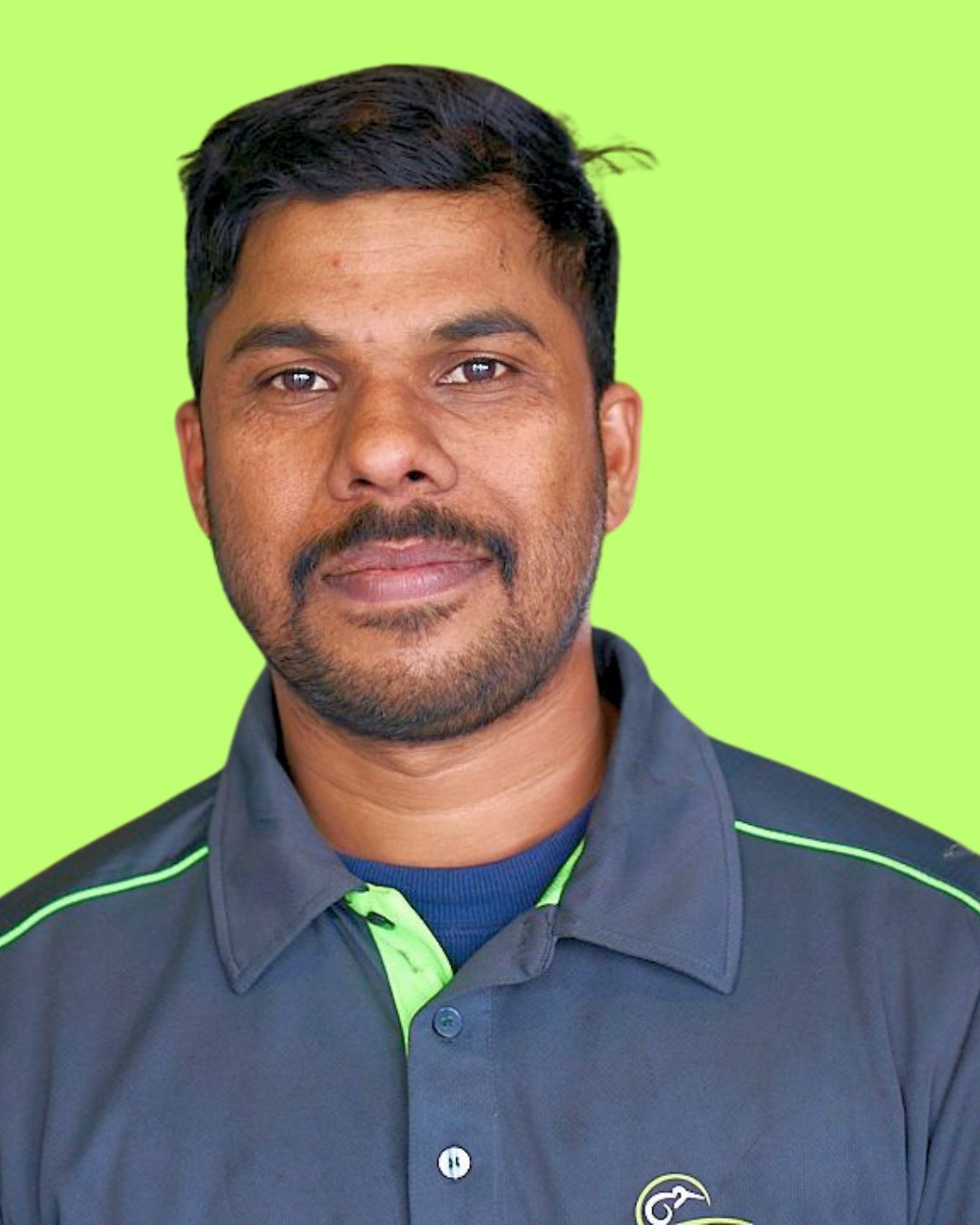 A man with a beard is standing in a garage and smiling for the camera.