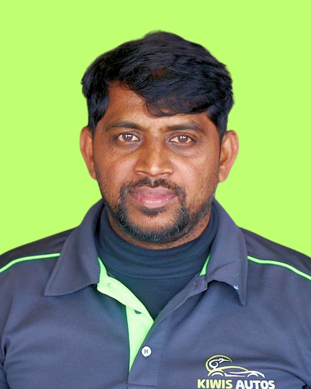 A man with a beard is wearing a black and green shirt.