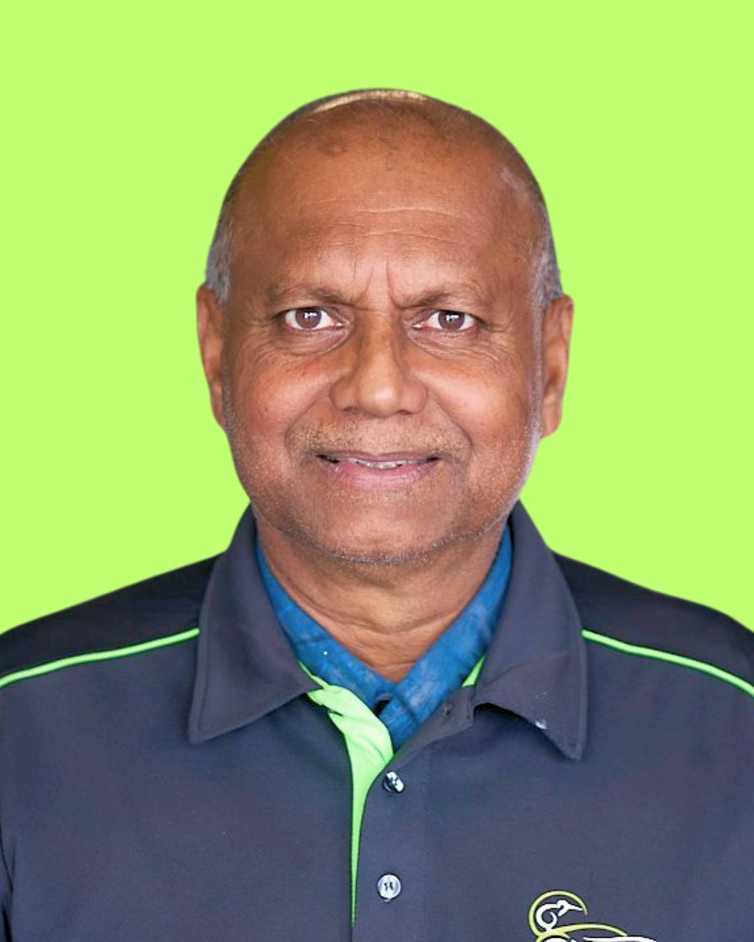 A man in a black and green shirt is smiling for the camera in a garage.