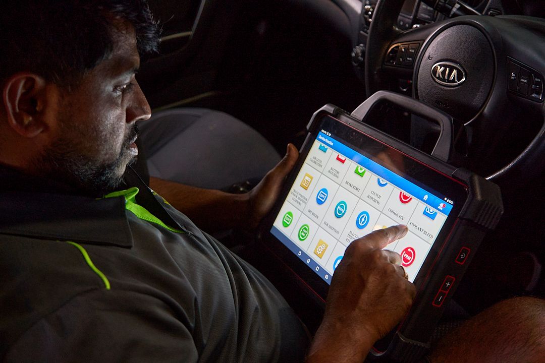 A man is sitting in a car using a tablet computer.