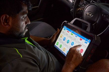 A man is sitting in a car using a tablet computer.