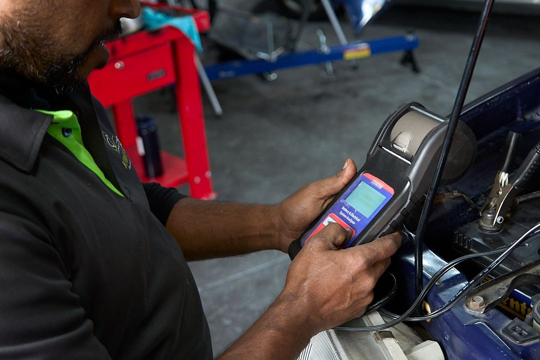 A man is using a device to check the battery of a car.