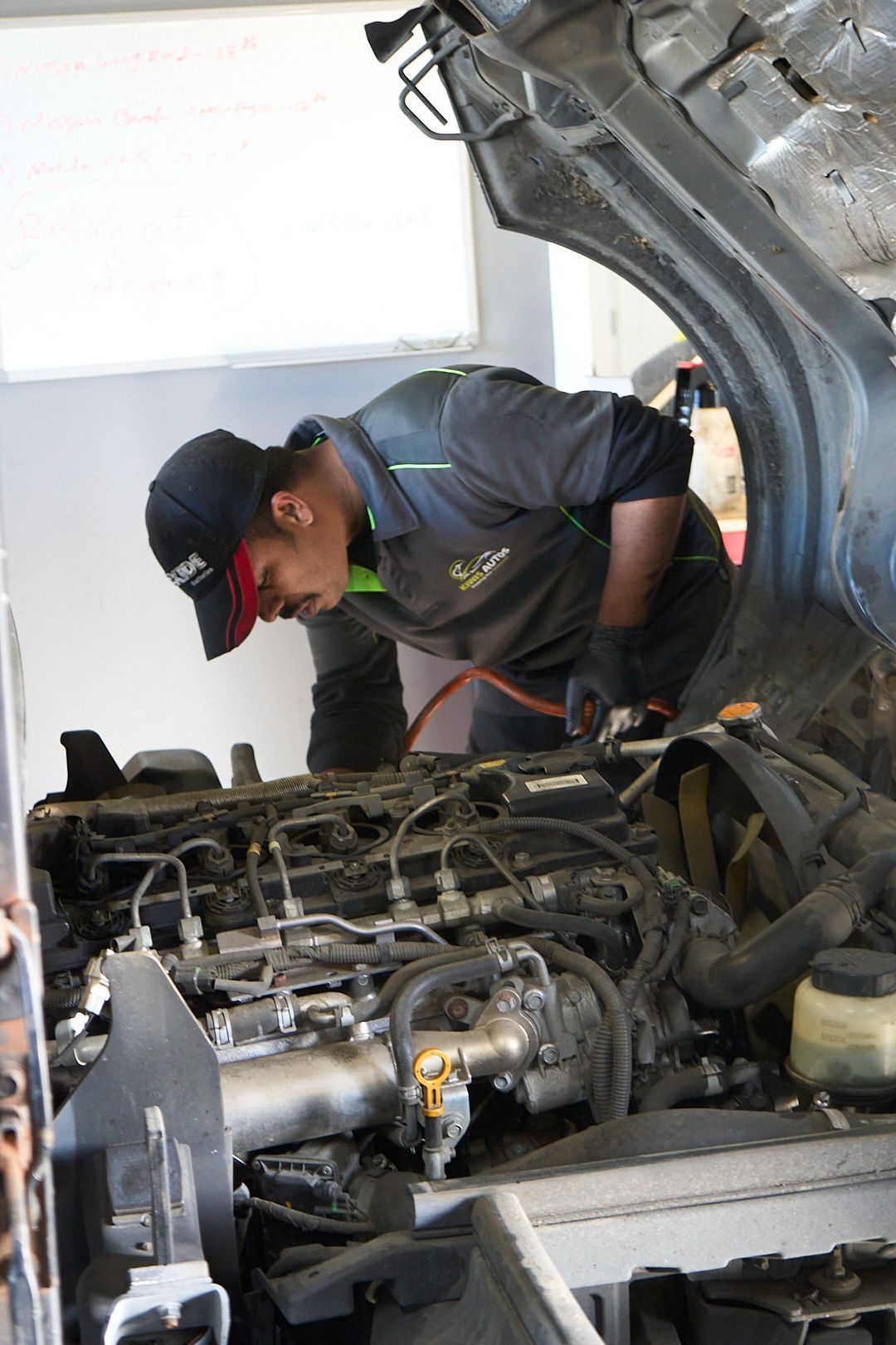 A man is working on a car engine with the hood open.