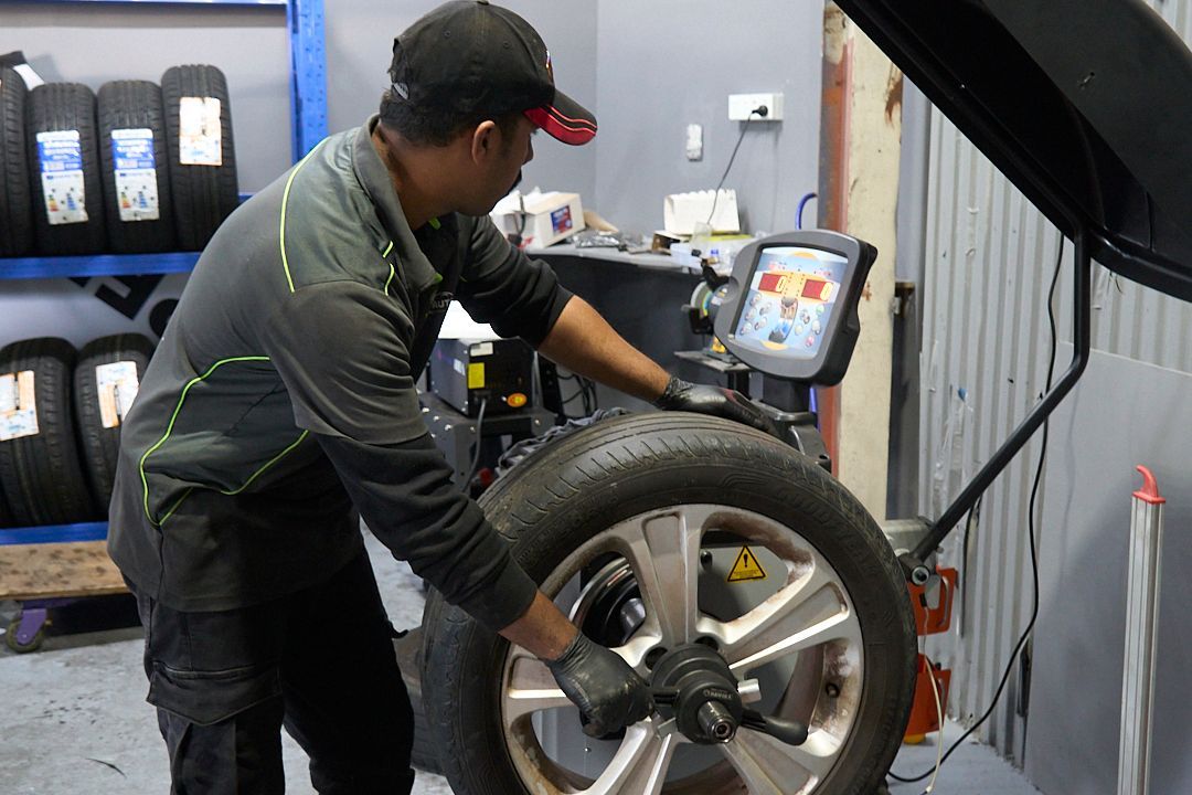 A man is balancing a tire in a garage.