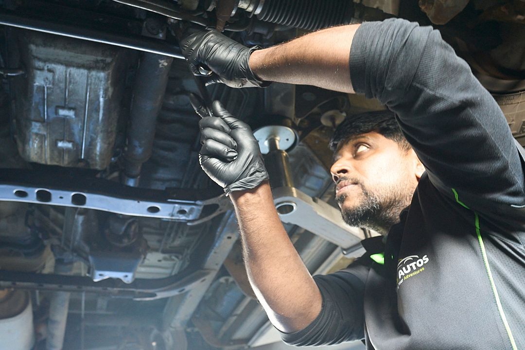 A man is working on the underside of a car.