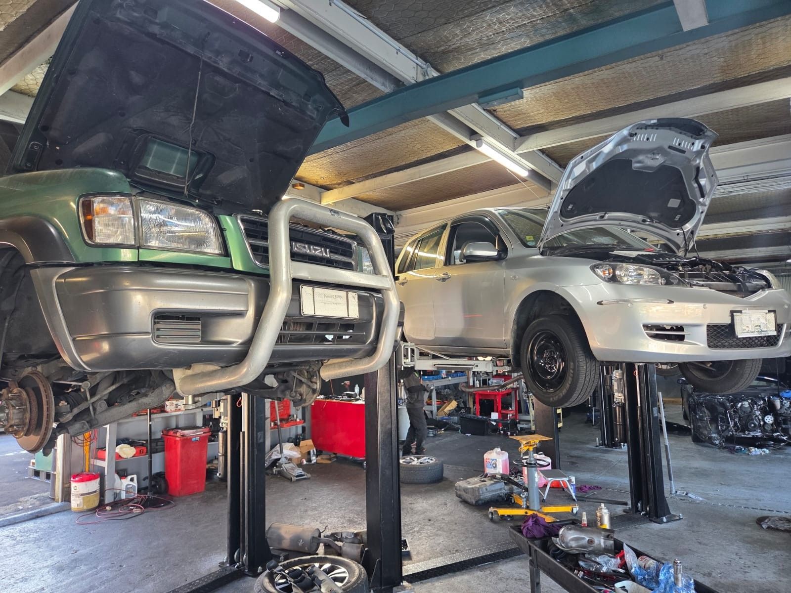 Two cars are sitting on a lift in a garage.