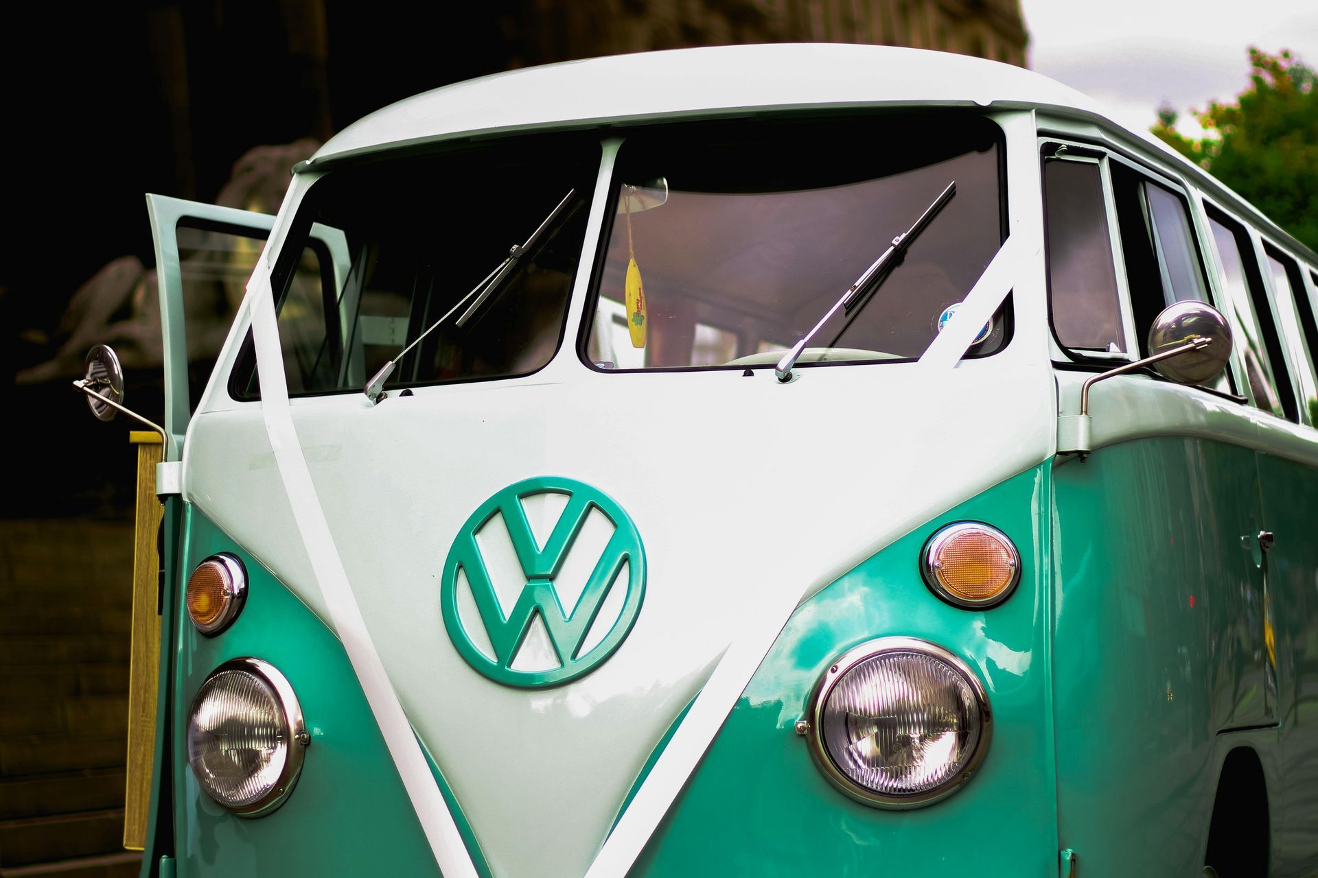 A green and white vw bus is parked in front of a building.