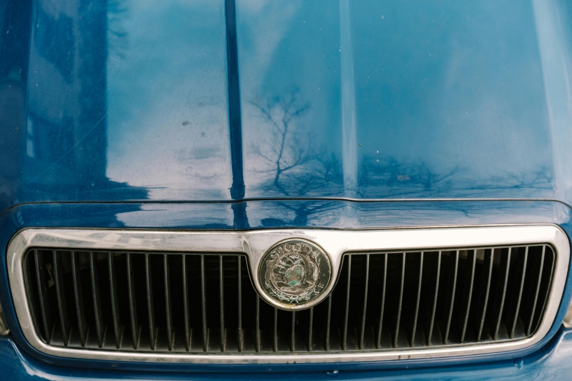A close up of a blue car 's hood and grill